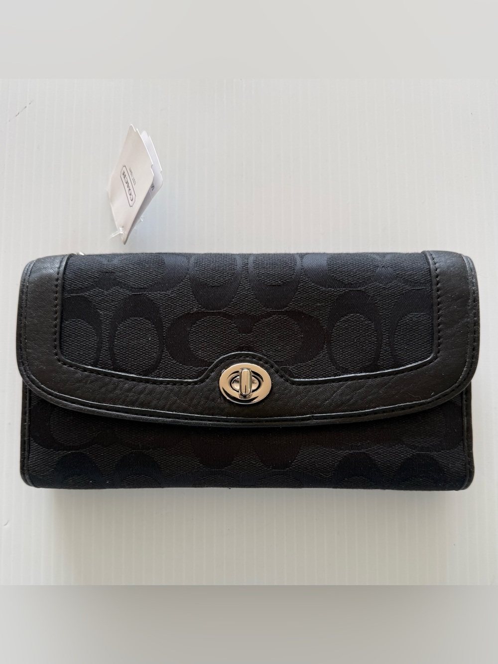 Coach Signature canvas trifold wallet featuring a turnlock closure leather trim